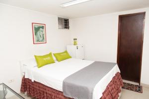 a bedroom with a large white bed with green pillows at Ayenda 1131 Casa Valencia in Manizales