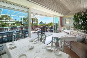un restaurant avec des tables et des chaises blanches et un balcon dans l'établissement Los Granados I, Puerto Banus, Marbella, à Marbella