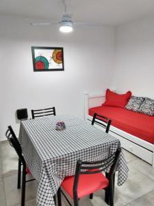 um quarto com uma mesa e uma cama com lençóis vermelhos em La Recova em Alta Gracia