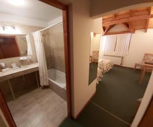 y baño con ducha, lavabo y bañera. en Hotel Spa Nieves Del Cerro en Caviahue