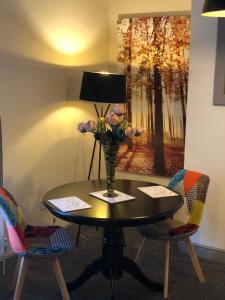 a table with a vase of flowers on it with chairs at The Old Inn at Plover Cottage Lindley in Huddersfield