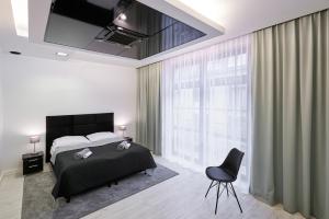 1 dormitorio con 1 cama, TV y silla en Prestige Apartamenty VINCI Centrum, en Kielce