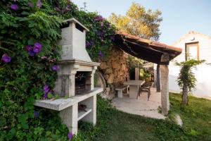 a stone fireplace in the yard of a house with purple flowers at Casa de Santa Cristina in Alpendurada