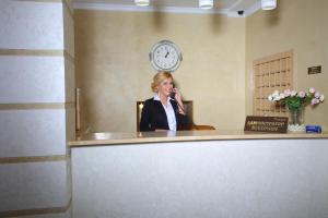 a woman talking on a phone in a room with a clock at Hotel Dobrodiy in Vinnytsya