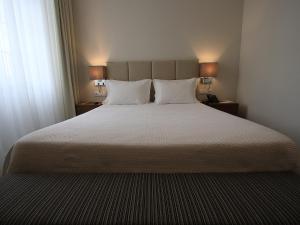 - une chambre avec un grand lit blanc et deux lampes dans l'établissement Consolata Hotel, à Fátima