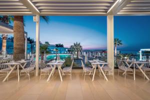 a patio with tables and chairs and a view of the ocean at Mitsis Rodos Village in Kiotari