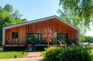 une grande grange en bois avec une terrasse couverte dans l'établissement Village de vacances Les Lambrilles, à La Bastide-de-Sérou