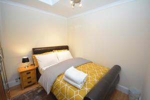 a small bedroom with a bed and a night stand at London Luxury 5 Bedroom House 2 min walk to the Tube Station in Dagenham