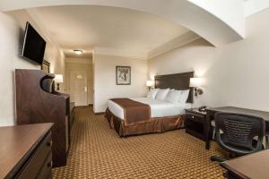 a hotel room with a bed and a desk and a television at Baymont by Wyndham Galveston in Galveston