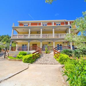 una gran casa amarilla con una escalera delante de ella en Apartments Veselka, Lumbarda, en Lumbarda