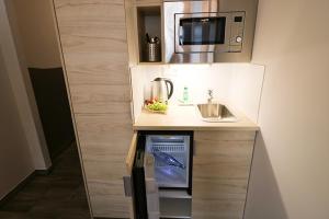 a small kitchen with a sink and a microwave at Petul Apart Hotel An'ne 40 in Bochum