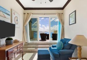 a living room with a blue couch and a large window at Villa Anguillitta in Blowing Point Village