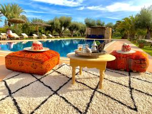 une piscine avec une table et deux chapeaux dans l'établissement Marrakech Retreat By La Siredrah, à Marrakech