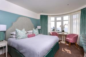 a bedroom with a bed with blue walls and windows at Roslin Beach Hotel in Southend-on-Sea