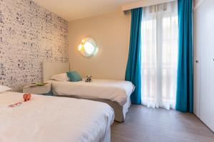 ドーヴィルにあるRésidence Pierre & Vacances Premium Presqu'Ile de la Touquesのベッド2台と窓が備わるホテルルームです。