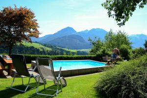 uma piscina com cadeiras e um homem nas montanhas em Lammerauhof em Abtenau