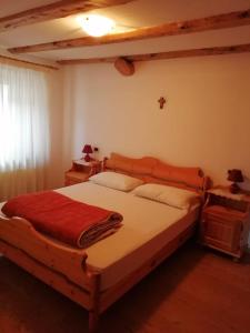 una camera da letto con un letto con una coperta rossa sopra di Giovanna Ribul Moro a Padola