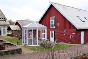 a red barn with a greenhouse in front of it at Danhostel Faxe in Faxe