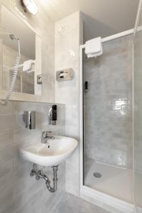 a white bathroom with a sink and a shower at a&o Graz Hauptbahnhof in Graz