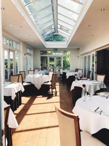 un restaurante con mesas y sillas blancas y tragaluz en Fishmore Hall Hotel and Boutique Spa, en Ludlow