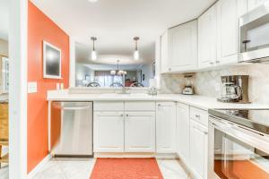 una cocina con armarios blancos y una pared de color naranja en Plantation Club 464, en Hilton Head Island