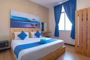 a bedroom with a large bed with blue curtains at Paretto Seaview Hotel in Pantai Cenang