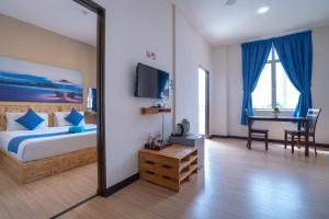 a hotel room with a bed, tv and a desk at Paretto Seaview Hotel in Pantai Cenang