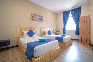 a bedroom with two beds with blue pillows at Paretto Seaview Hotel in Pantai Cenang