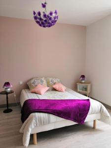 Un dormitorio con una cama con sábanas moradas y una lámpara de araña. en Le Manoir du Gouverneur en Villedieu-le-Château