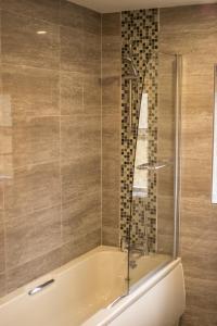 un baño con bañera y ducha de cristal en Haddon Cottage - Darwin Lake Holiday Village, en Matlock 8 fotos más