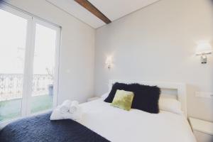 a bedroom with a white bed and a large window at Arrasate - Local Rentss in San Sebastián