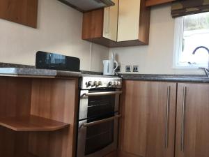 a kitchen with wooden cabinets and a stove top oven at 'Hartland Caravan' with Sea Views in Bideford