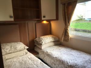 a small room with two beds and a window at 'Hartland Caravan' with Sea Views in Bideford