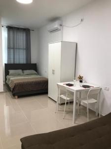 a bedroom with a bed and a white table and chairs at Isramax Apartment near the sea. in Bat Yam