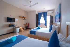 a hotel room with two beds and a television at Paretto Seaview Hotel in Pantai Cenang