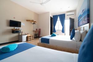 a hotel room with two beds and a television at Paretto Seaview Hotel in Pantai Cenang