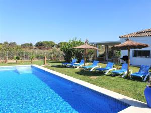 a swimming pool with lounge chairs and umbrellas at Casa Rural El Pinar de Jesus in Arcos de la Frontera