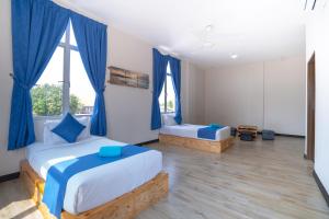 a bedroom with two beds and blue curtains at Paretto Seaview Hotel in Pantai Cenang