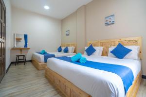a bedroom with two beds with blue pillows at Paretto Seaview Hotel in Pantai Cenang