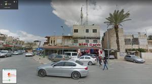 una concurrida calle de la ciudad con coches aparcados en la calle en MOUNT41 Hostel en Jericho