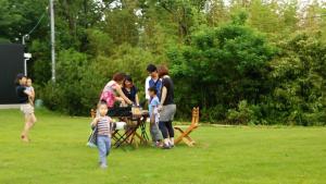 un grupo de personas de pie alrededor de una mesa de picnic en un parque en Guest house Third Place, en Sado