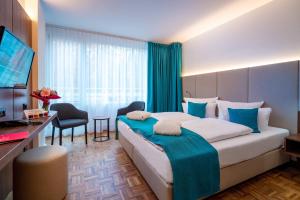 バート・ズルツァにあるHotel an der Therme Bad Sulzaの大きなベッドとデスクが備わるホテルルームです。