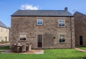 a brick house with a table and chairs in front of it at Haddon Cottage - Darwin Lake Holiday Village in Matlock