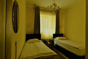 a bedroom with two beds and a mirror and a window at Jamilya B&B Guest House in Karakol