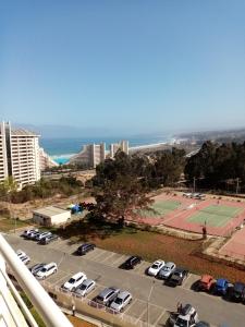 un aparcamiento con coches aparcados y una pista de tenis en Departamento Laguna Bahía, en Algarrobo