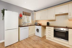 a kitchen with white cabinets and a washer and dryer at Hopton Cottage - Darwin Lake Holiday Village in Matlock