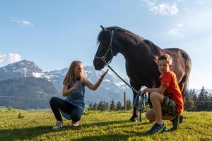 a boy and a girl with a horse in a field at Lammerauhof in Abtenau