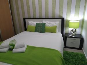 um quarto com uma cama branca e um cobertor verde em Casa da Liberdade em Nazaré na Nazaré