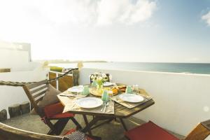 a table and chairs on a balcony with a view of the ocean at SoulSurfcamp Portugal in Peniche