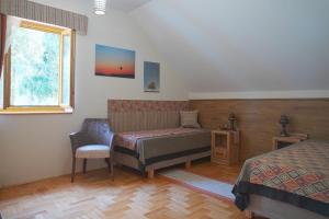 um quarto com uma cama, uma cadeira e uma janela em Alirét Vadászház em Ságvár